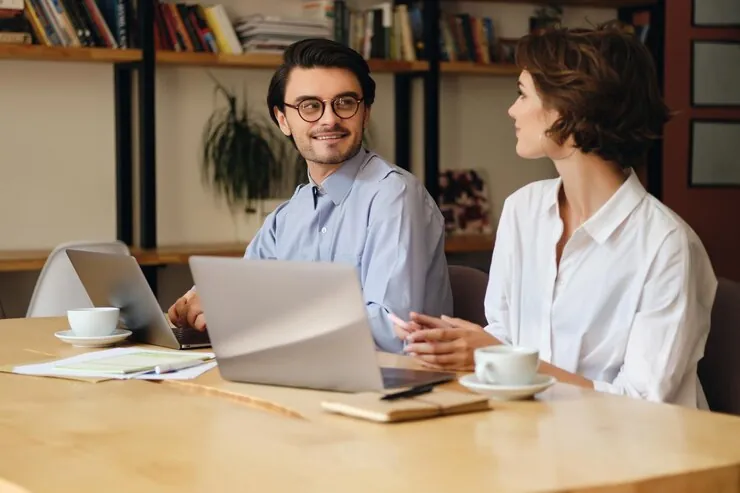 An accountant and a client talking at a table with laptops and cups of coffee